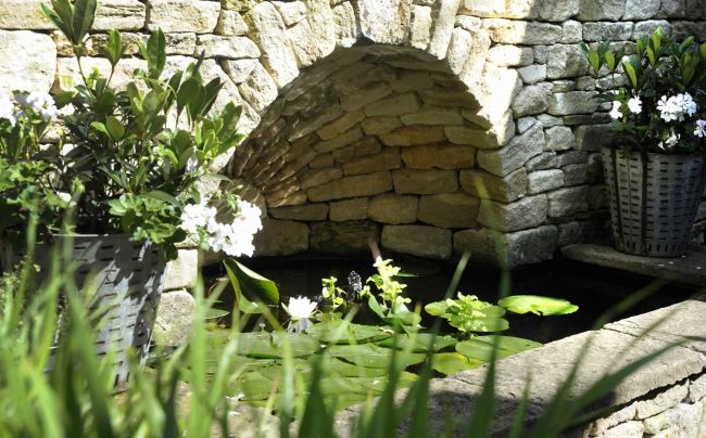 A familiar local feature has inspired this archway set into a retaining wall, providing space for a small pond